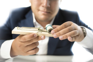 closeup photo of man in suit taking money out of mousetrap