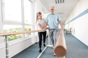 Physical therapist assisting patient after hip replacement surgery.